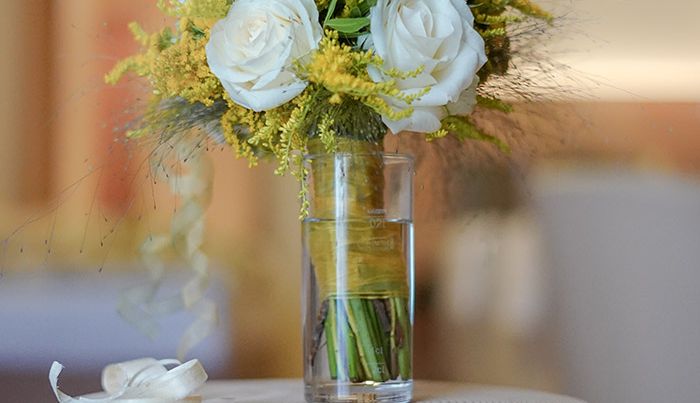 Ein eleganter Blumenstrauß mit weißen Rosen und gelben Akzenten in einer Glasvase