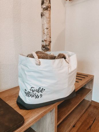 Weiße Tasche mit der Aufschrift 'Wald Wellness' in einem Zimmer im Hotel Lärchenhof