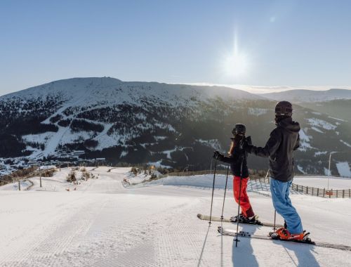 Skipiste im Sonnenschein mit Skifahrern