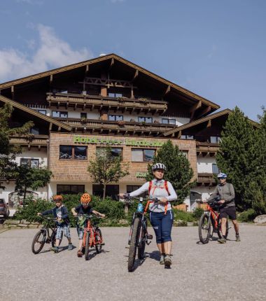 Eine Familie mit Fahrrädern steht vor dem Hotel Lärchenhof am Katschberg, bereit für eine Radtour in den Bergen