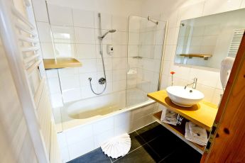Modernes Badezimmer im Hotel Lärchenhof mit rundem Waschbecken und Spiegel