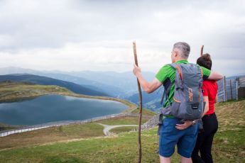 Ein Paar genießt den Ausblick auf den Speichersee und die umliegenden Berge am Aineck in der Nähe des Hotel Lärchenhof