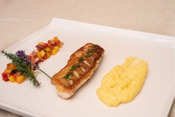 Ein feines Fischgericht, angerichtet mit buntem Gemüse und cremiger Polenta, serviert im Hotel Lärchenhof am Katschberg