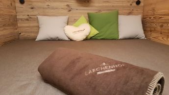 Ein kuscheliger Ruhebereich im Waldwellness-Bereich des Hotels Lärchenhof, mit einer großen Liege und weichen Kissen