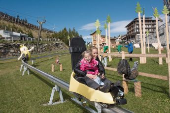 Zwei Kinder sitzen in einem Spaßzug im Freizeitpark am Katschberg und genießen die Fahrt durch die grüne Landschaft