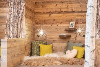 Eine gemütliche Kuschelecke mit Holzwänden, weichen Kissen und warmem Licht im Hotel Lärchenhof