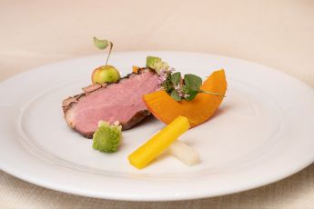 Ein Teller mit einem raffinierten Fleischgericht, garniert mit Gemüse und Kräutern im Hotel Lärchenhof