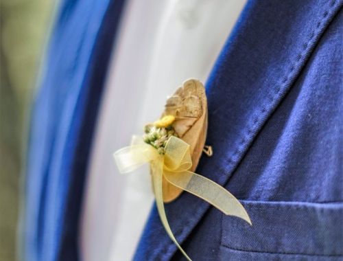 Ein Bräutigam in einem blauen Anzug trägt einen eleganten Anstecker aus Blumen, passend zur Waldhochzeit im Hotel Lärchenhof